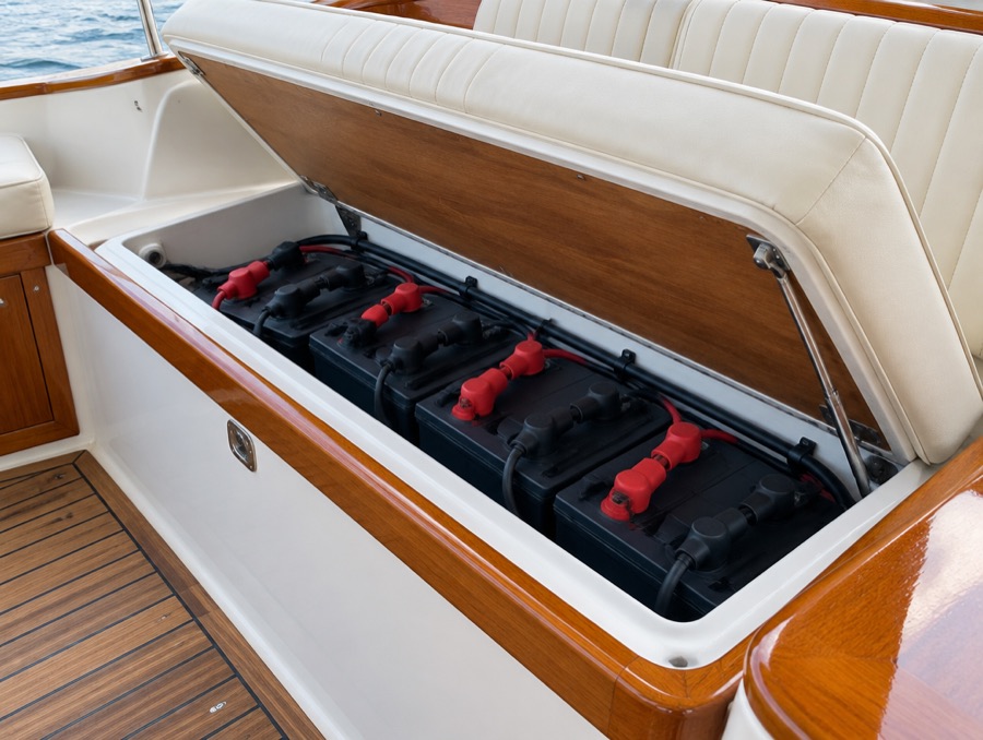Deep-cycle batteries in the locker beneath a Duffy's bench seat, teak hatch lifted open